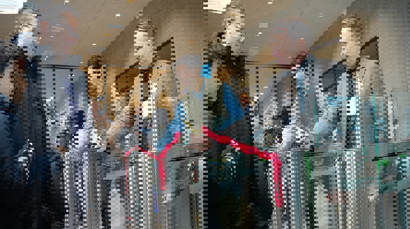 To mænd klipper røde snore ved indgang til svømmehal. 